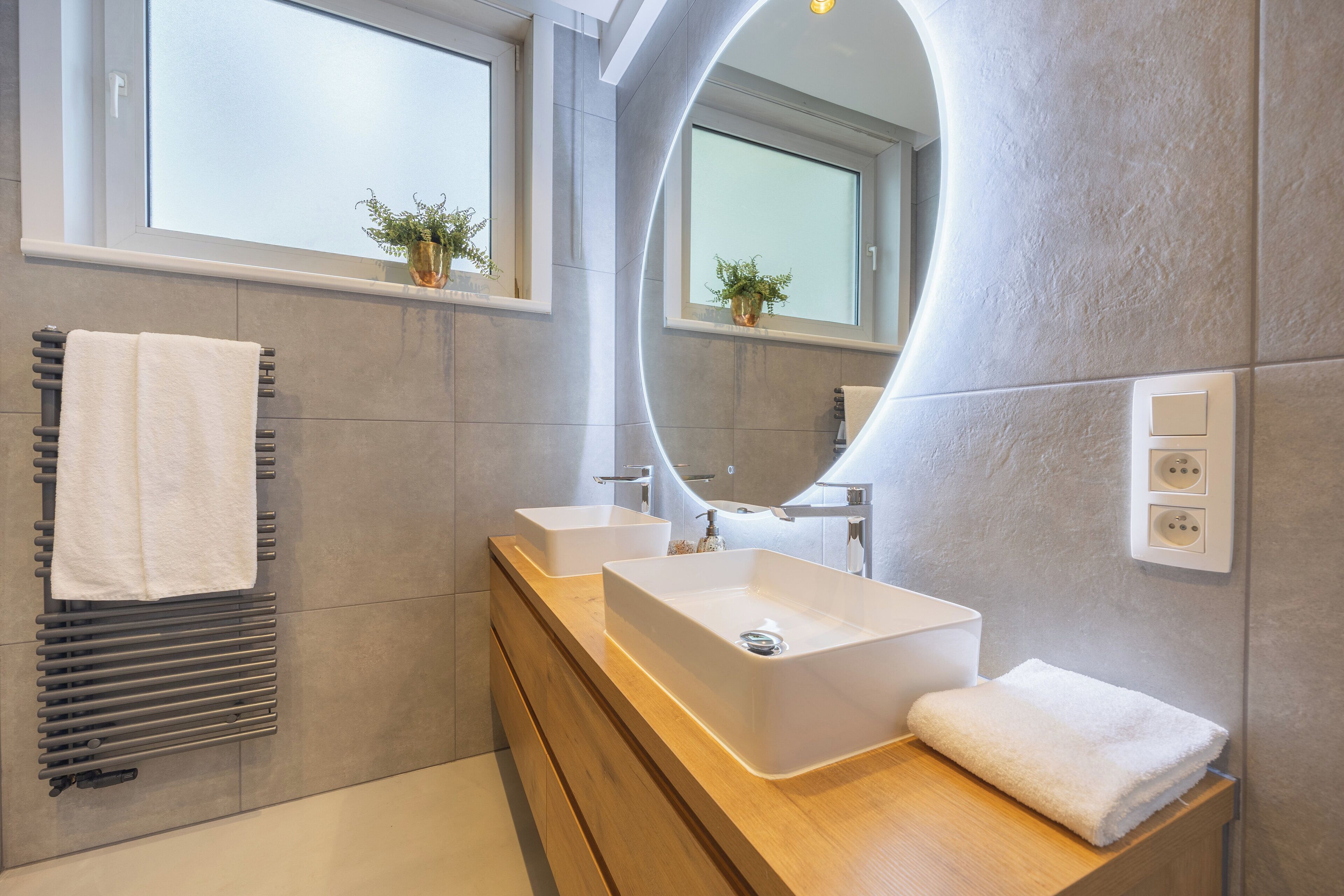 Een moderne badkamer met twee wasbakken, een grote spiegel en een handdoekhouder.