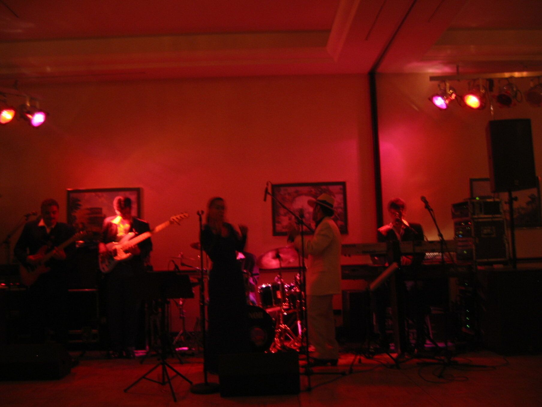 Una banda tocando en una sala tenuemente iluminada con luces rojas.