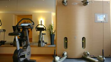 Ein Fitnessraum mit Trainingsgeräten, einem Spiegel und einer Holzwand mit Bedienfeld.