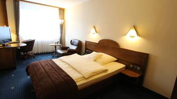 Une chambre d’hôtel avec un lit, un bureau, une chaise et un téléviseur.
