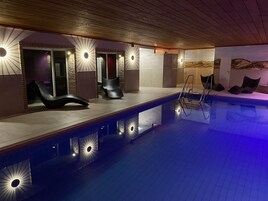 Una piscina techada, sillones reclinables de piscina