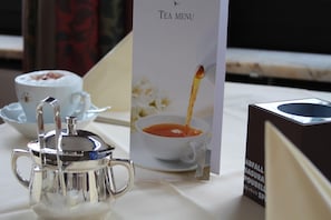 A tea service setup with a teapot, cups, and a menu on a table.