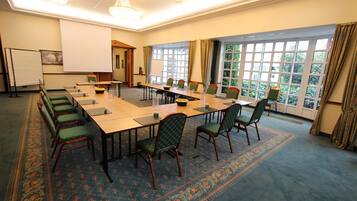 A conference room with a long table, chairs, a projector screen, and a carpeted floor.
