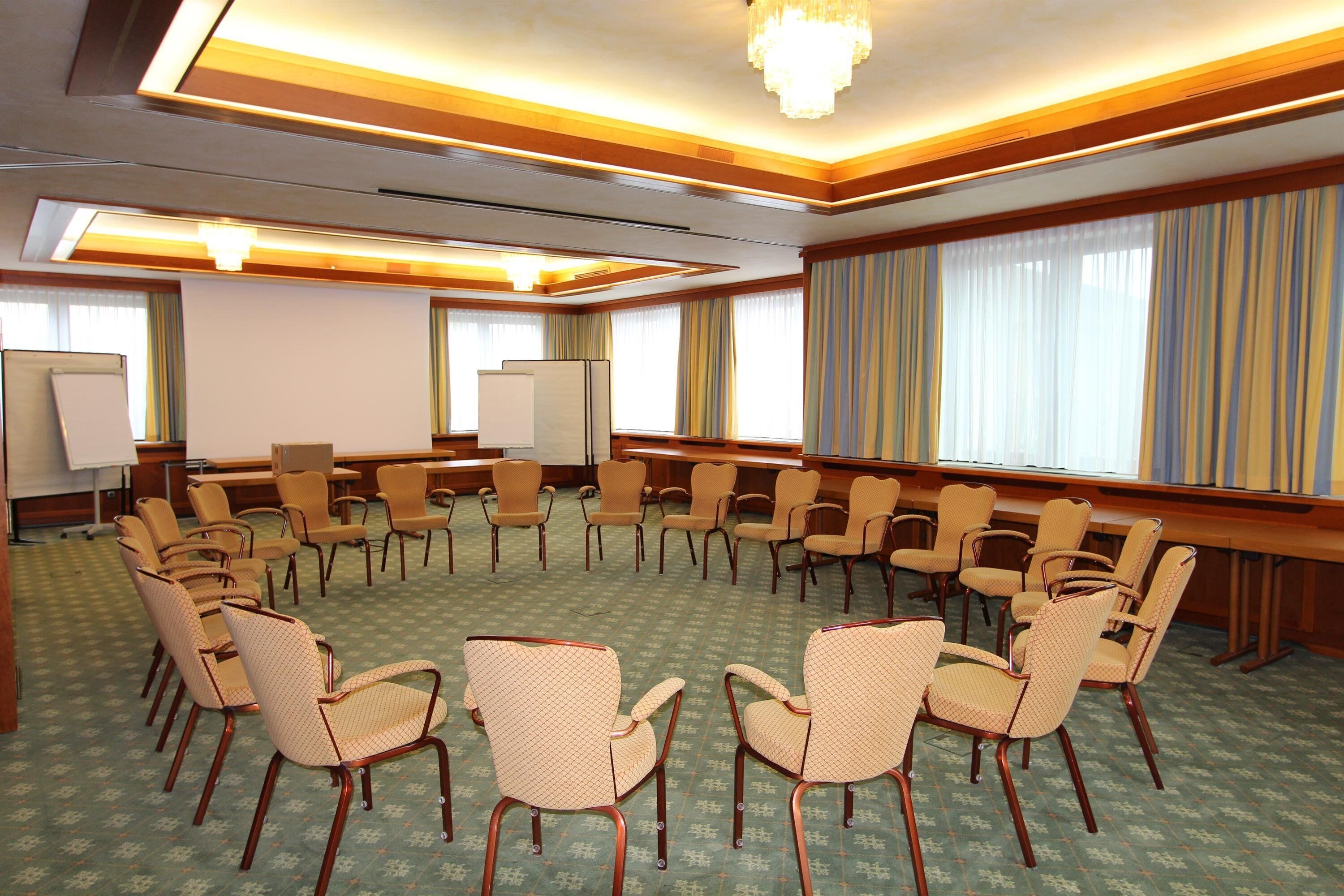 Una sala de conferencias con sillas dispuestas en círculo, una pizarra y una pantalla de proyector.