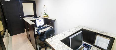 A modern office with a desktop computer, a monitor, and a keyboard on a marble countertop.