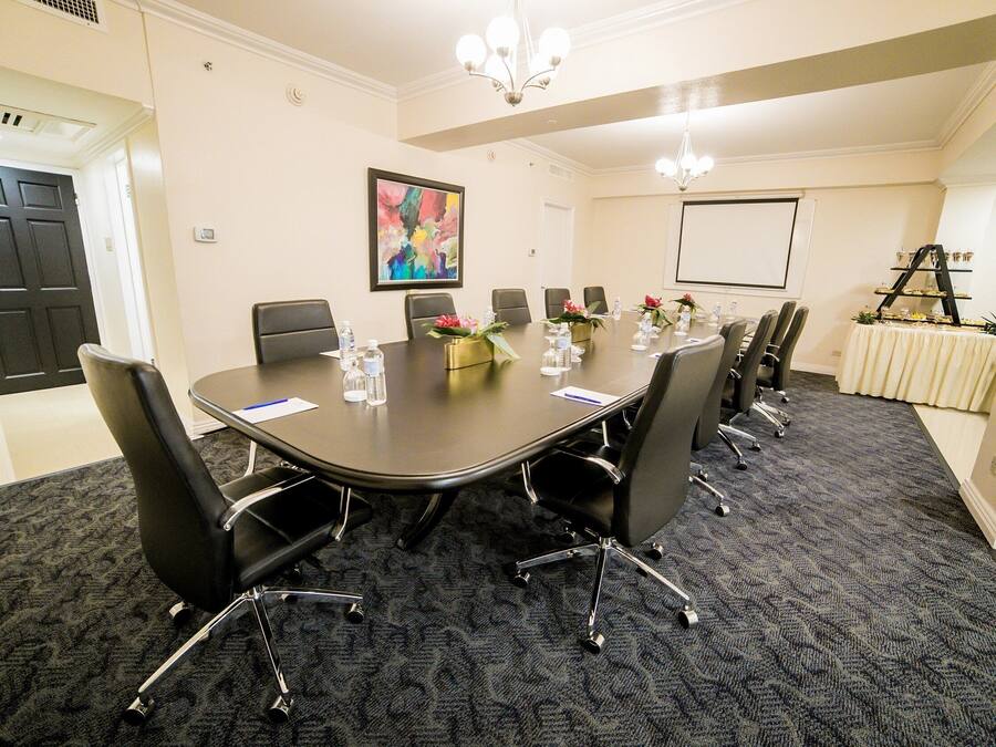 A conference room with a large table, black chairs, and a carpeted floor.