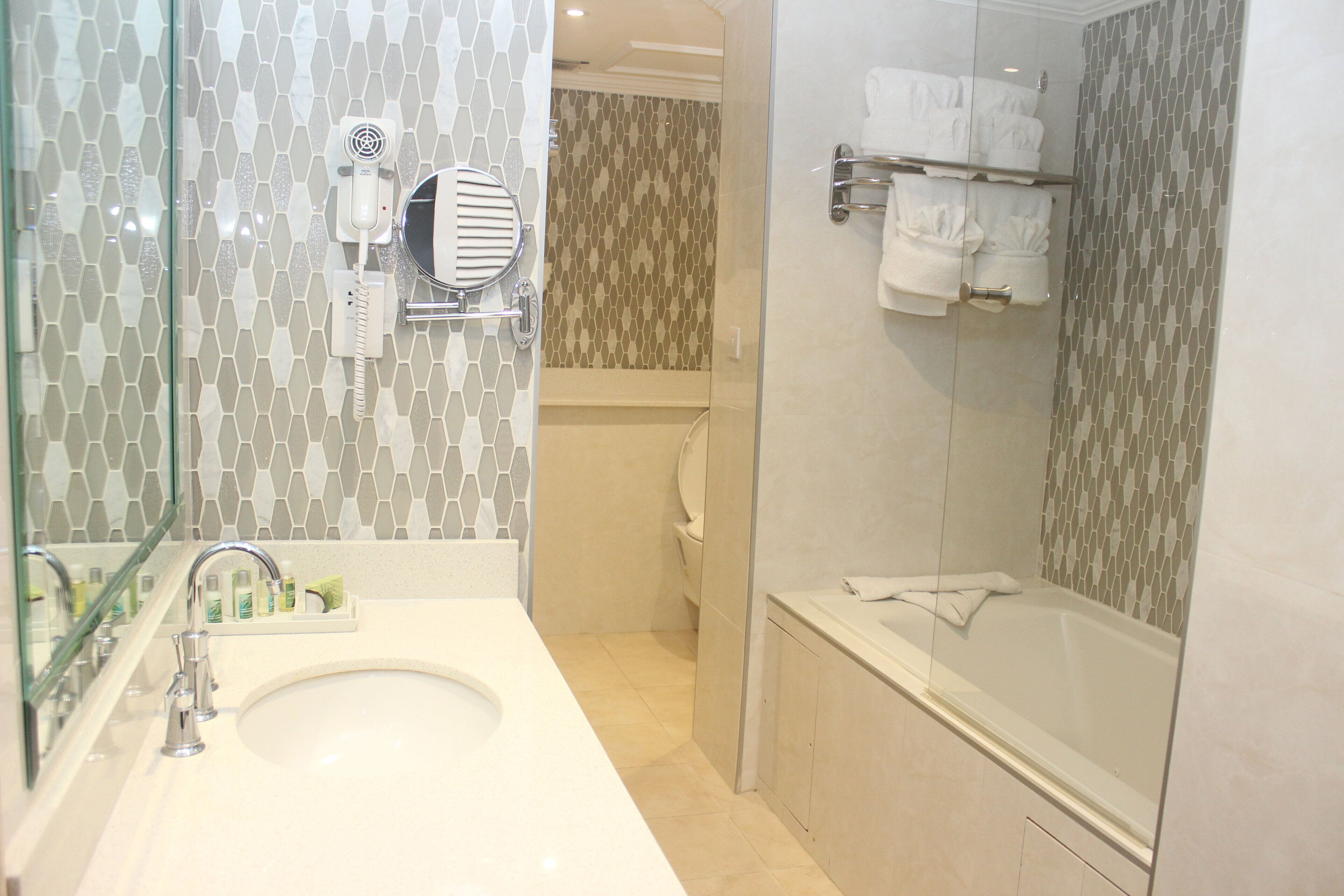 A bathroom with a glass-enclosed shower, a white sink, and a mirror.