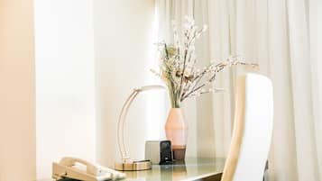 Balcão de hotel com um telefone, uma luminária e um vaso com flores.