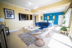 A spacious living room with a blue sofa, a white armchair, and a patterned rug.