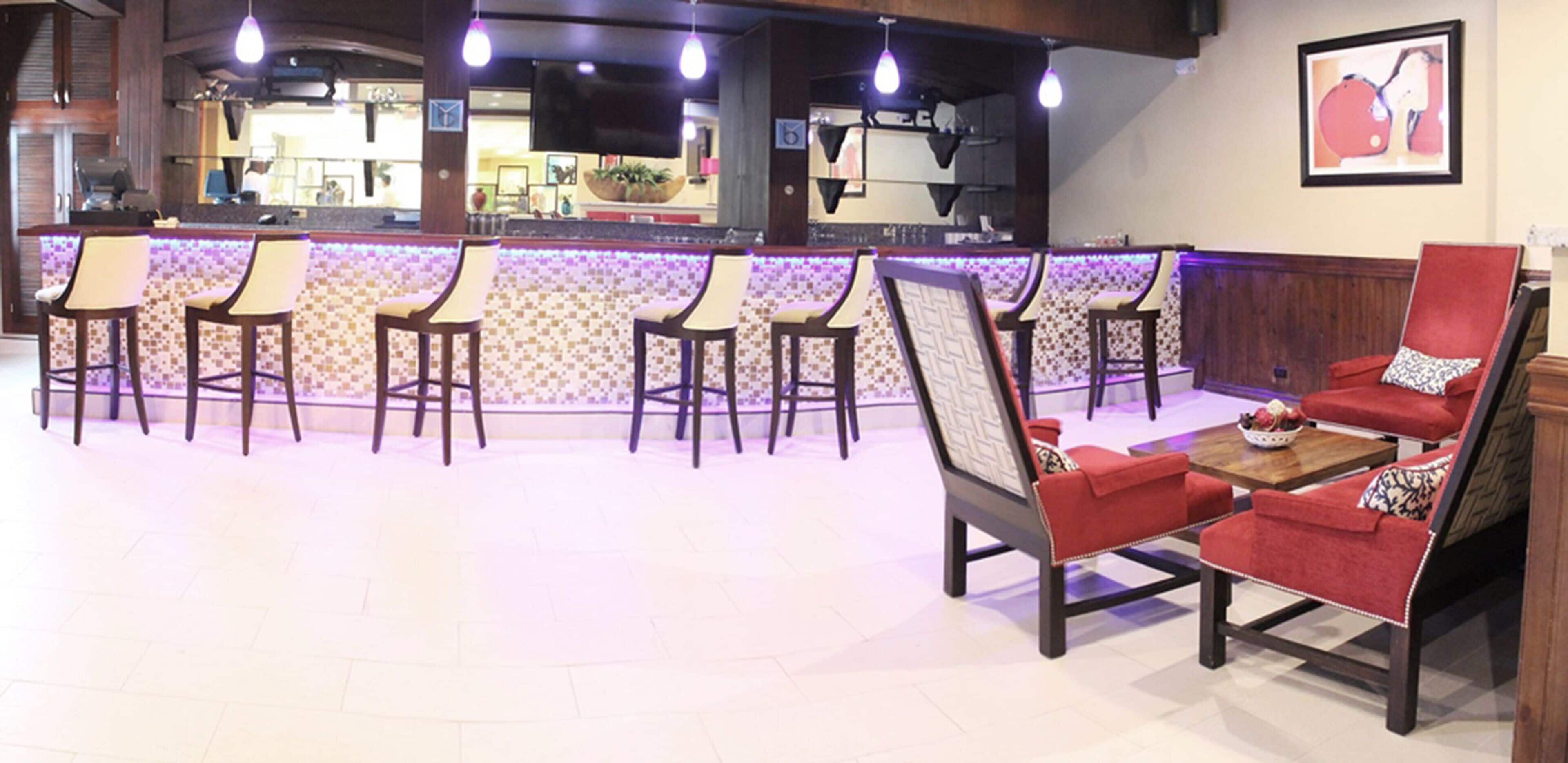 A bar area with multiple stools and a red sofa.