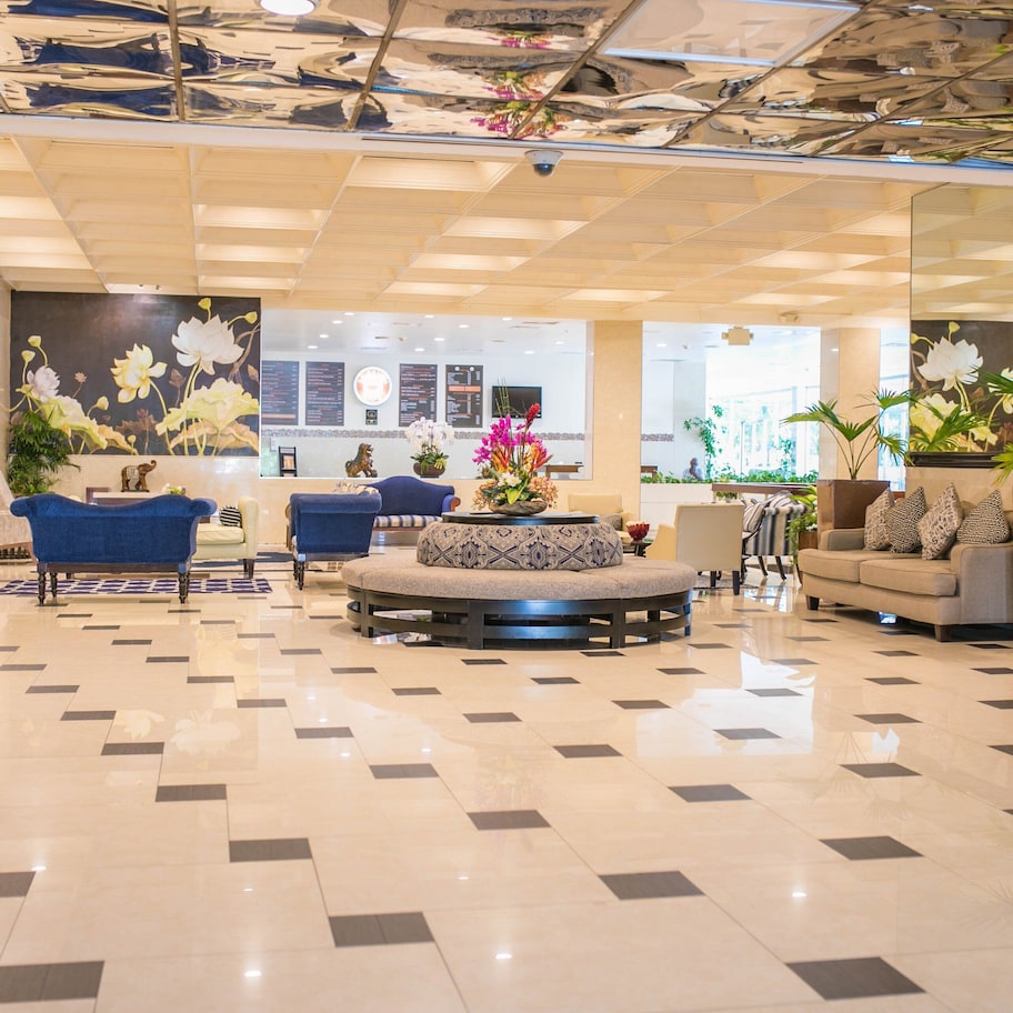 A spacious lobby with a checkered floor, a blue sofa, a round seating area, and a wall with floral decorations.