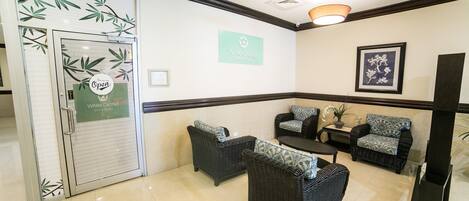 A reception area with a closed door, a sign indicating the business name, a framed floral artwork, and wicker furniture.