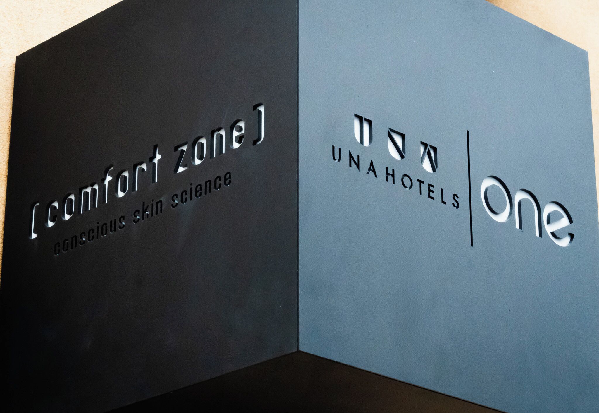 Two signs, one for 'Comfort Zone' and one for 'UnaHotels One,' with text indicating a focus on conscious skin science.