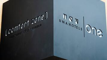 Two signs, one for 'Comfort Zone' and one for 'UnaHotels One,' with text indicating a focus on conscious skin science.