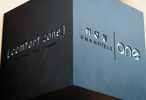 Two signs, one for 'Comfort Zone' and one for 'UnaHotels One,' with text indicating a focus on conscious skin science.