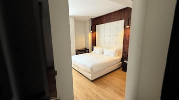 A bedroom with a large bed, wooden paneling on the walls, and a small bedside table.