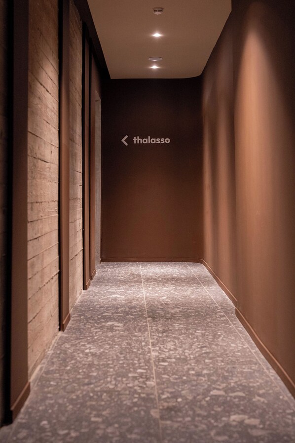 A hallway with a directional sign, a tiled floor, and a wall with a recessed ceiling light. - UNA Hotels One Catania Wellness & SPA (Catania)