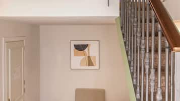 Une pièce de style « loft », avec un plancher en bois, un canapé, un tableau et un escalier doté d’une rampe en bois.