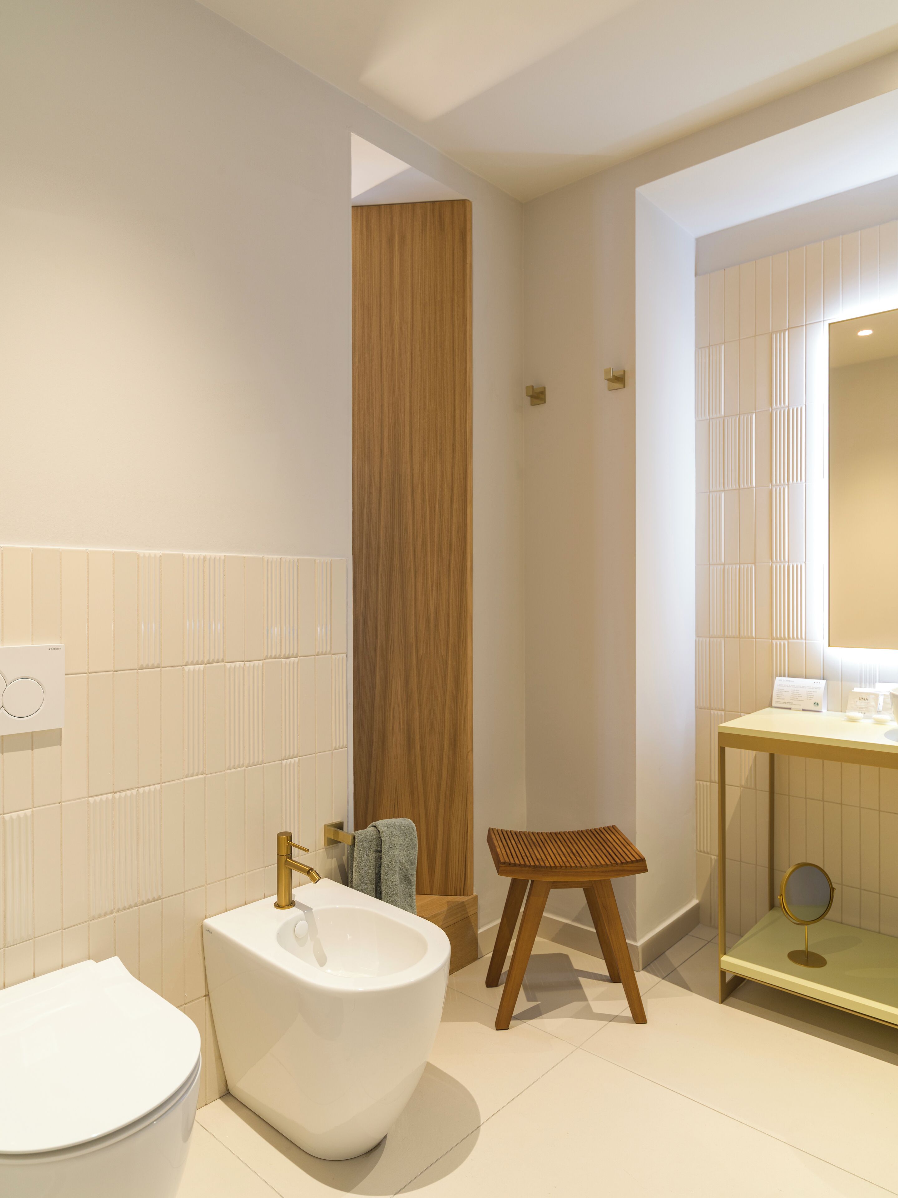 A modern bathroom with a freestanding bathtub, a wooden stool, and a vanity with a mirror.