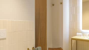 A modern bathroom with a freestanding bathtub, a wooden stool, and a vanity with a mirror.