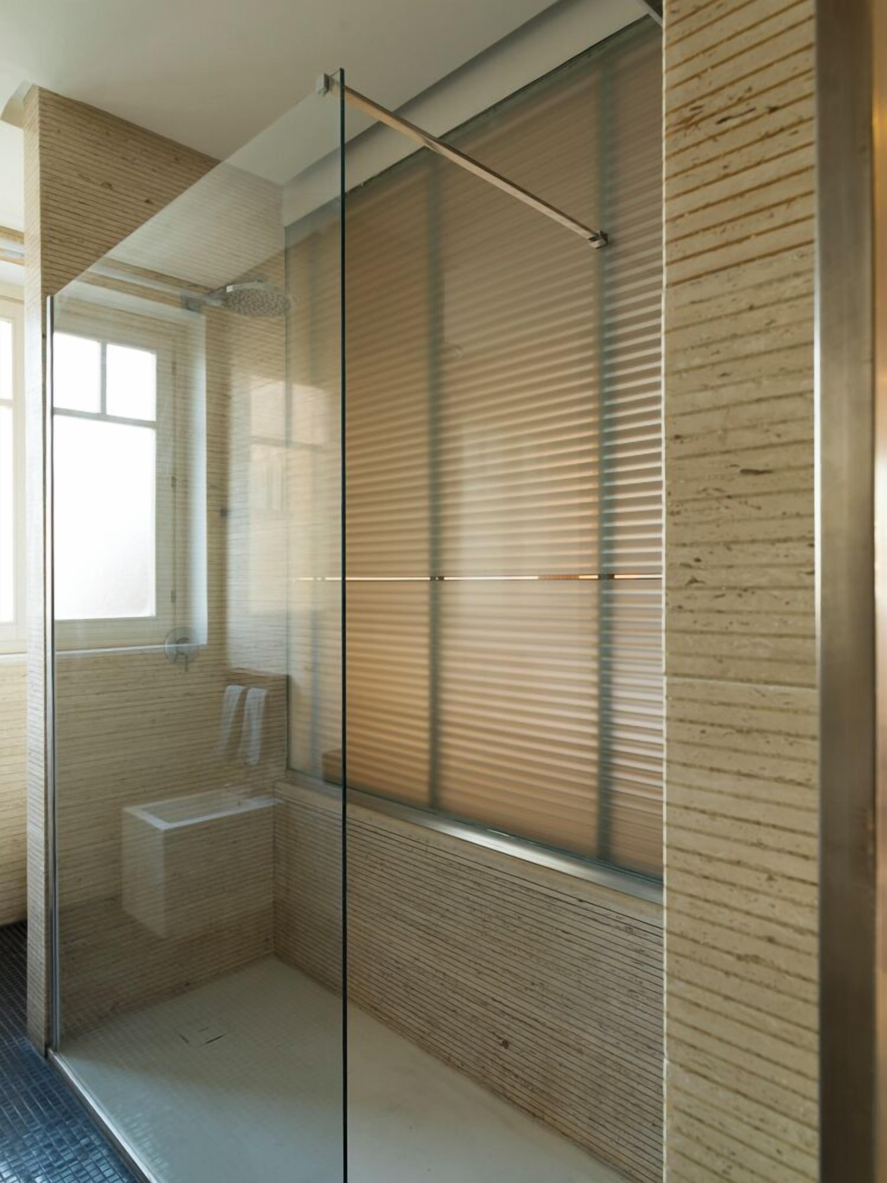 A modern bathroom with a glass shower enclosure, a toilet, and a sink.
