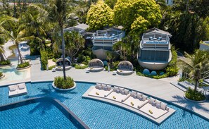 Un complejo turístico con una piscina grande, zonas de estar al aire libre y abundante vegetación.