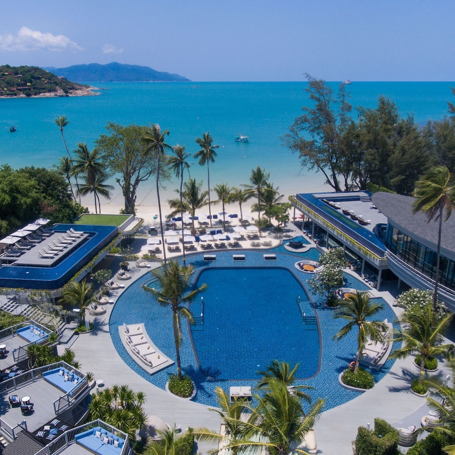 A resort with a large pool, sun loungers, and a view of the ocean.