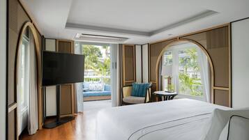 Habitación de hotel con una cama grande, televisión de pantalla plana, una mesita y una zona de estar con sofá y sillón.