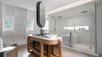A modern bathroom with a wooden vanity, a large mirror, a white sink, and a glass-enclosed shower.