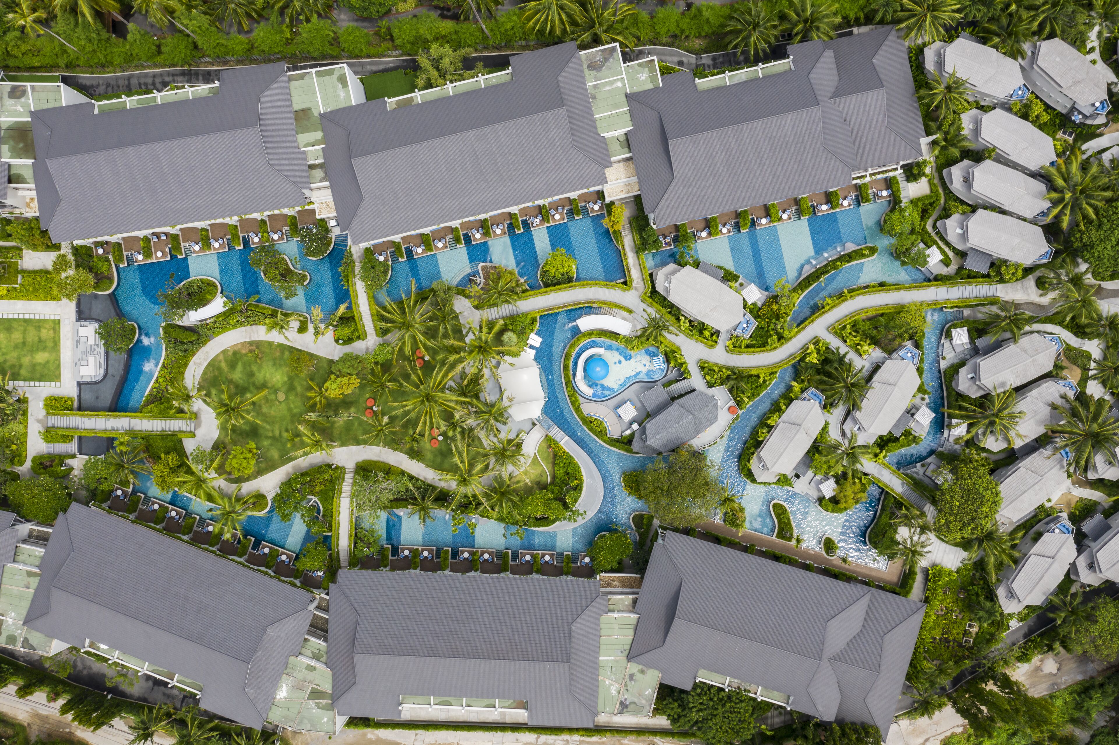 Vista aérea de un resort con varias piscinas, palmeras y edificios del complejo.