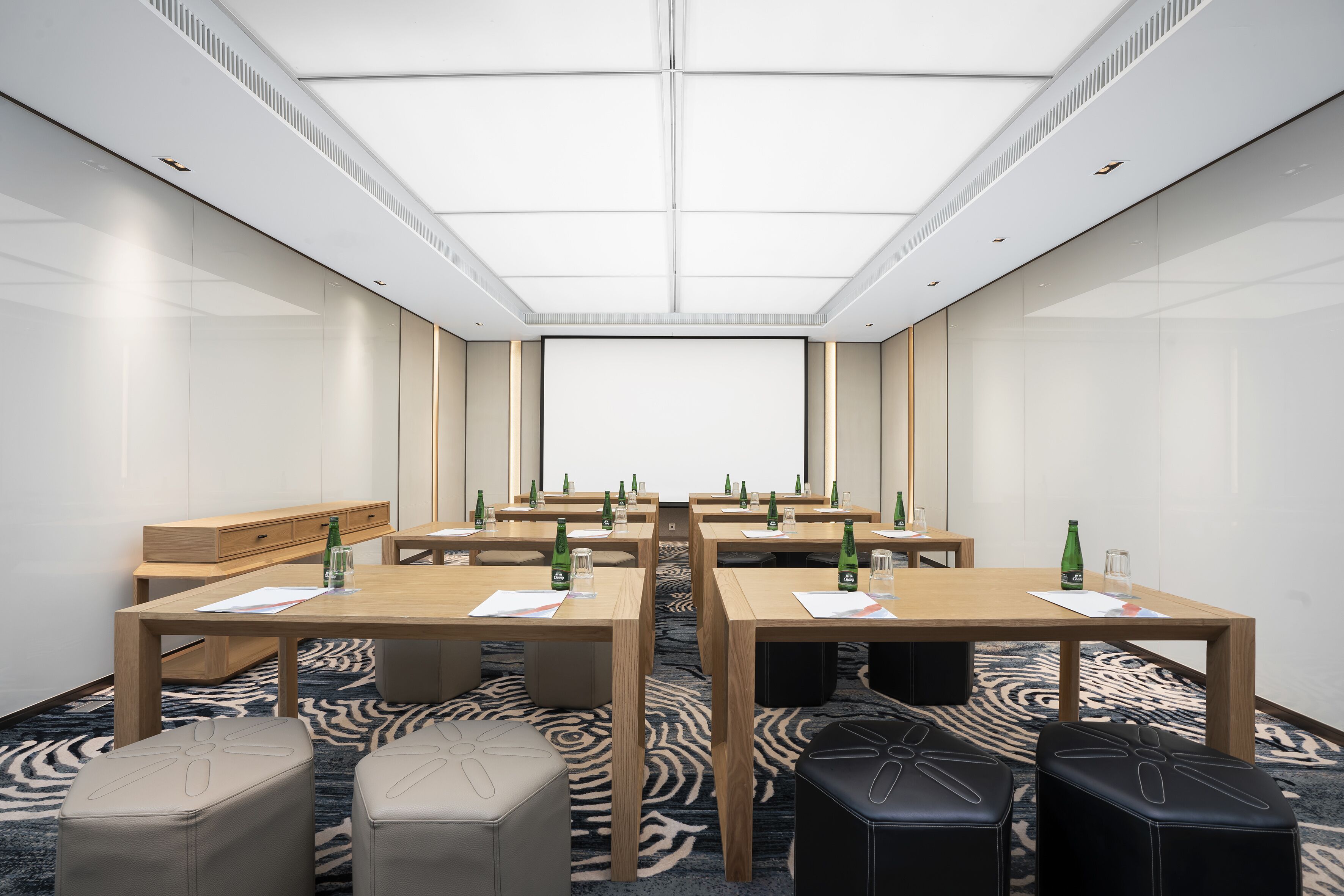 A conference room with a large table, chairs, and a carpeted floor.