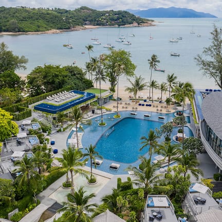 A resort with a large swimming pool, beach access, and views of the sea.