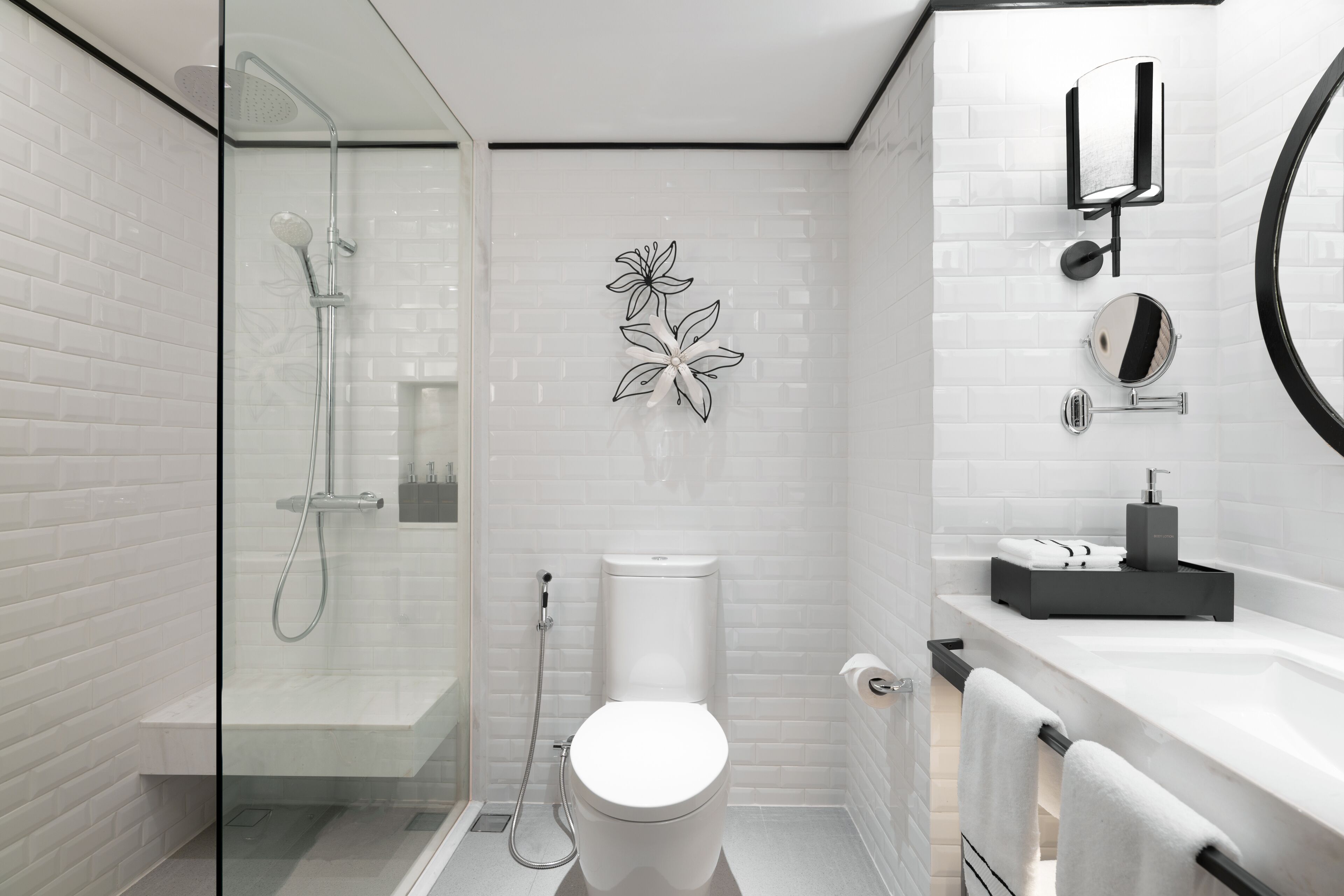 A modern bathroom with a glass-enclosed shower, a toilet, a sink, and a mirror.