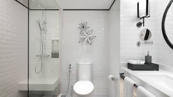 A modern bathroom with a glass-enclosed shower, a toilet, a sink, and a mirror.
