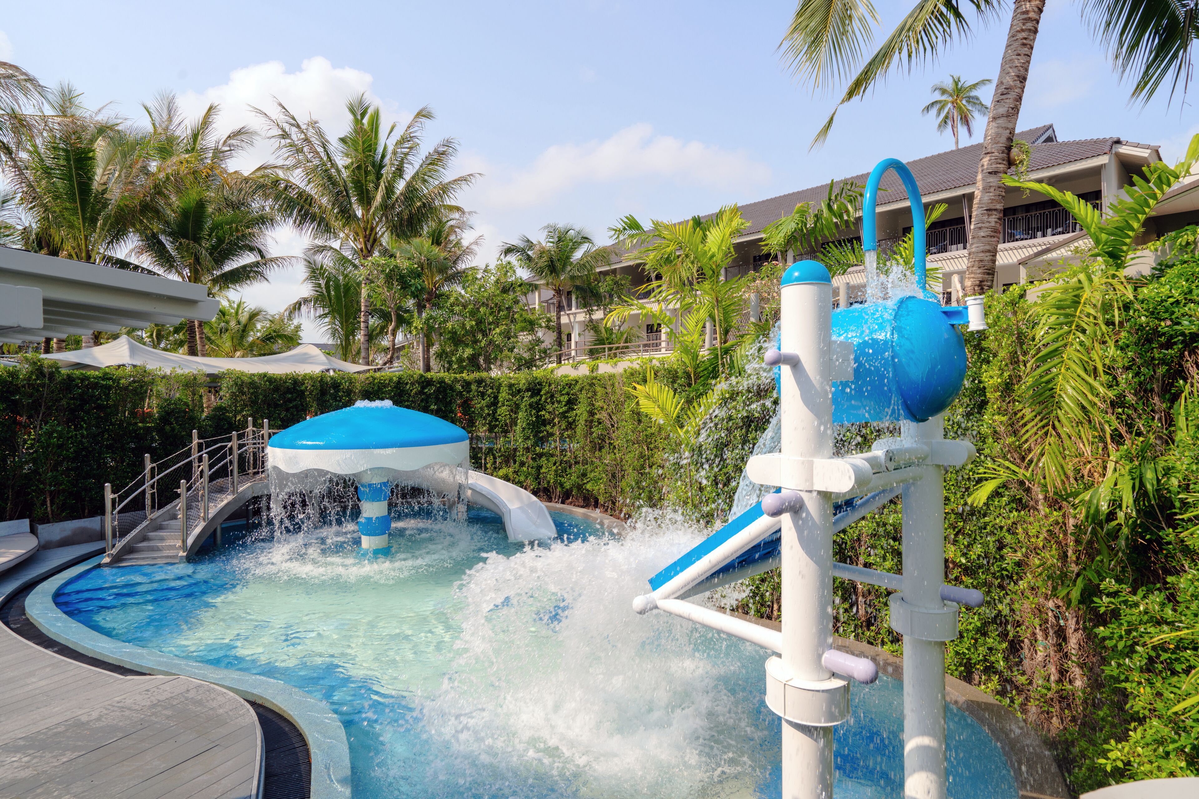 A water park area with a pool, water slides, and palm trees.
