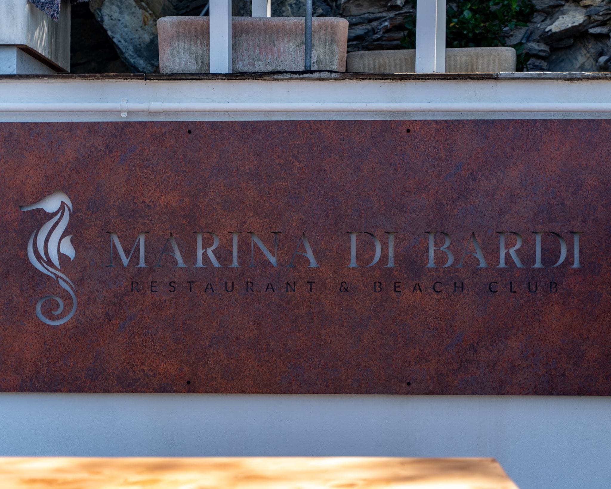 Schild für 'Marina Di Bardi Restaurant & Beach Club' mit stilisierter Seehorses-Grafik.