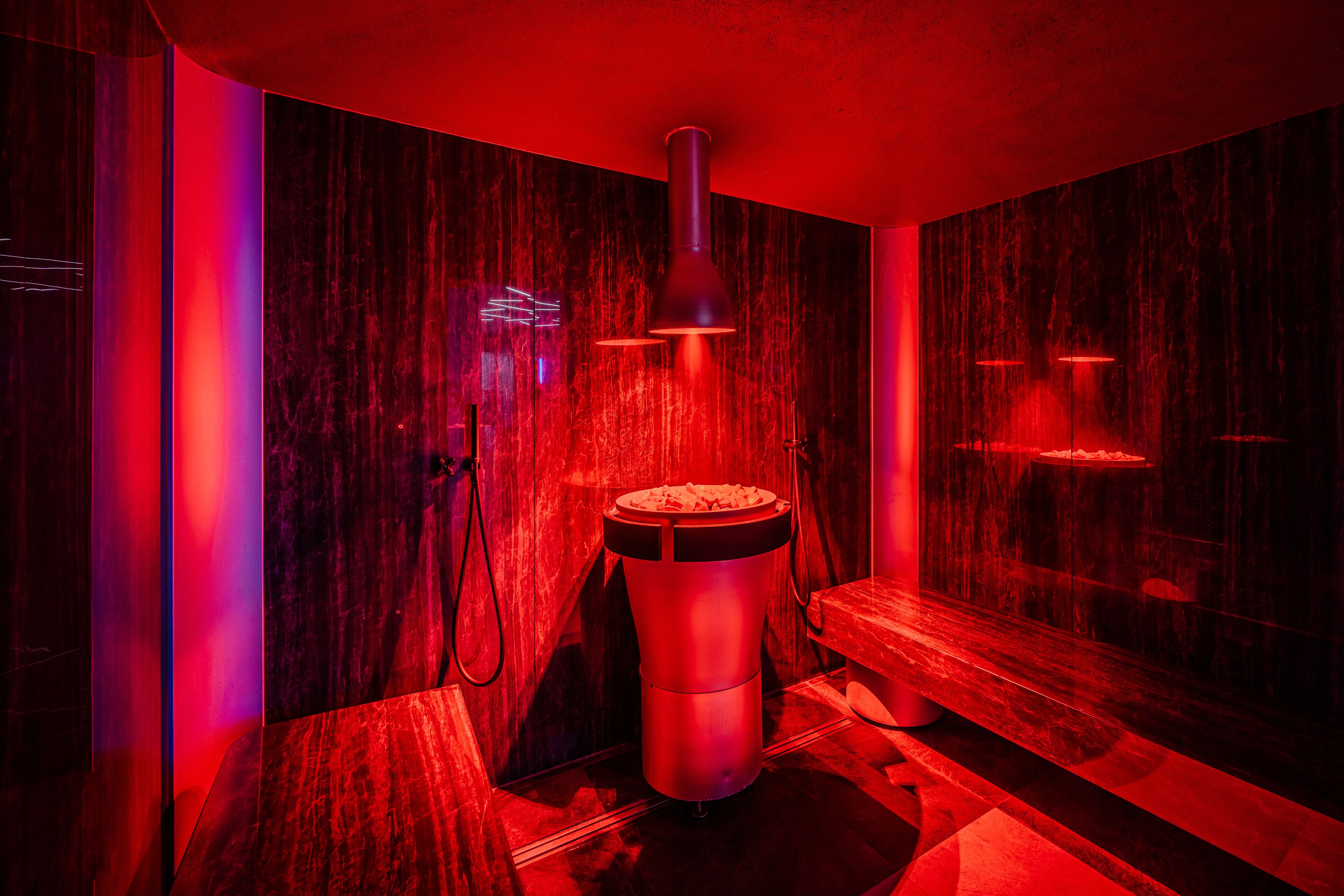 A sauna with a wooden bench and a central heating element.