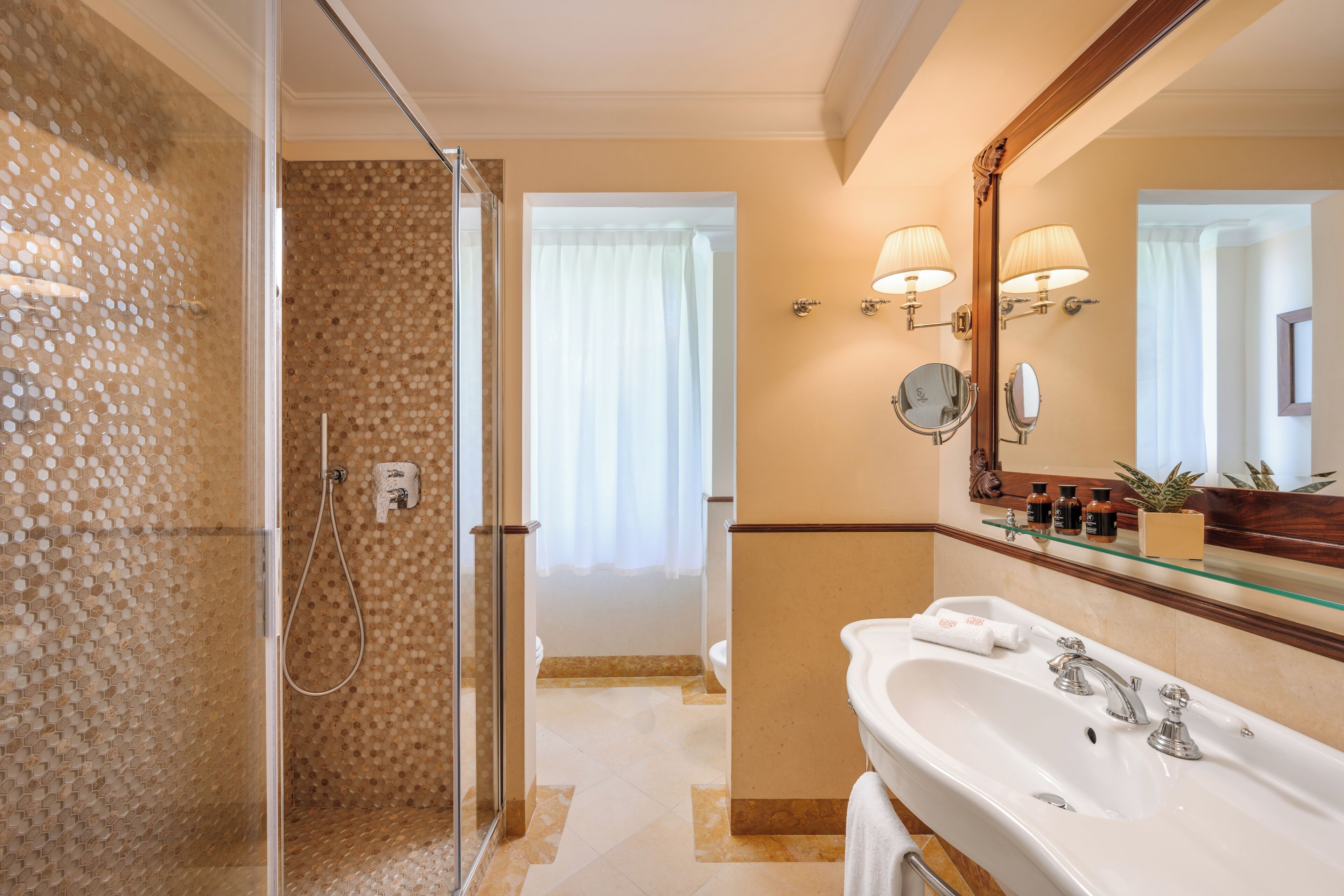 A modern bathroom with a glass shower enclosure, a large mirror, and a vanity with a sink and towel rack.