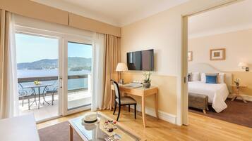 A hotel room with a balcony, a desk, a bed, and a television.