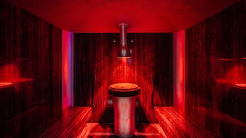 Un sauna con un calentador central que emite vapor, rodeado de paredes de madera y un suelo oscuro.
