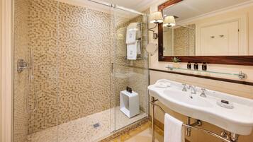 A modern bathroom with a glass-enclosed shower, a large sink, and a mirror with a wooden frame.