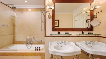 Un baño con ducha acristalada, dos lavamanos y un espejo grande con apliques de pared.
