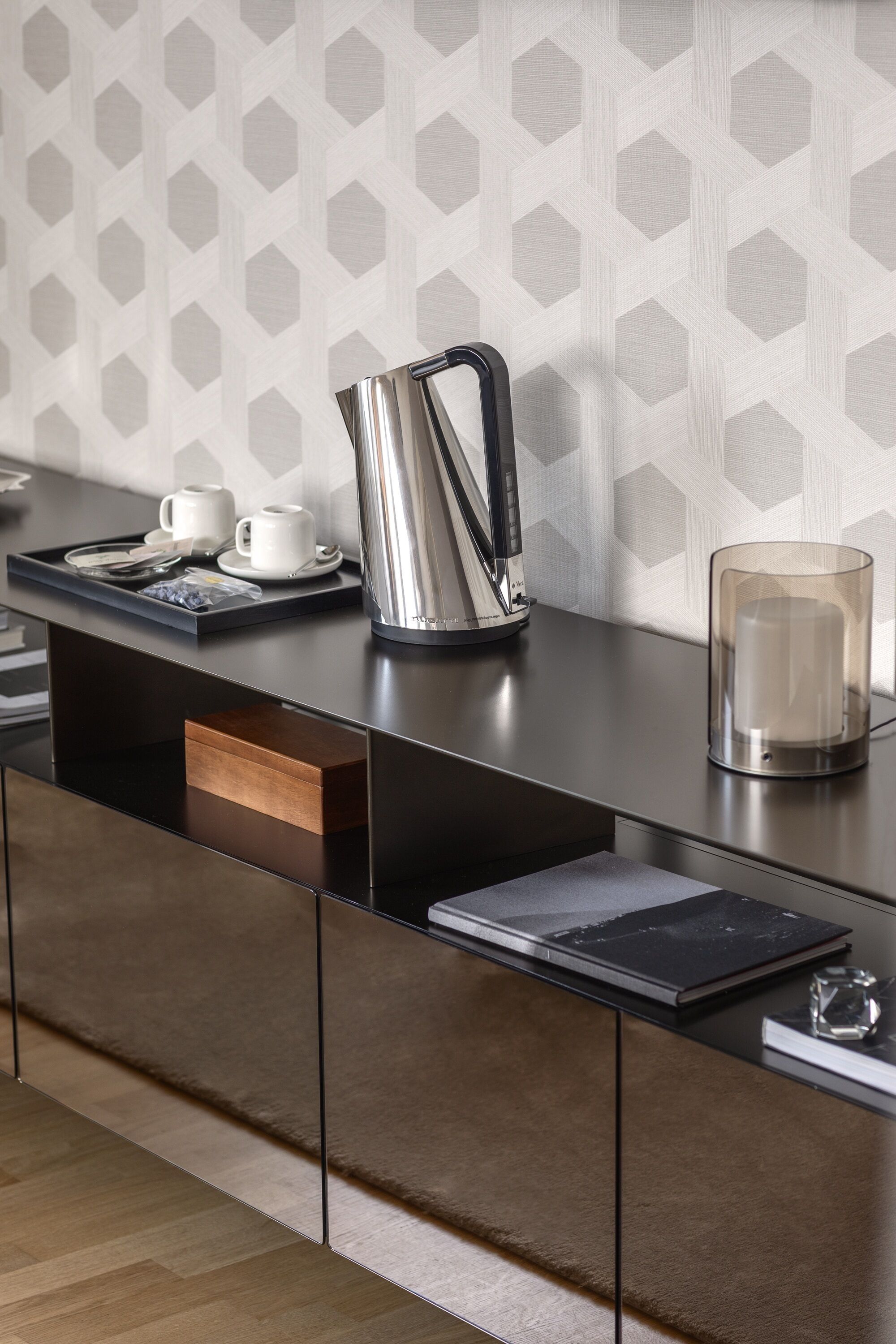 A modern kitchen with a sleek black countertop, a stainless steel kettle, and a clear glass container.