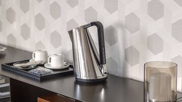 A modern kitchen with a sleek black countertop, a stainless steel kettle, and a clear glass container.