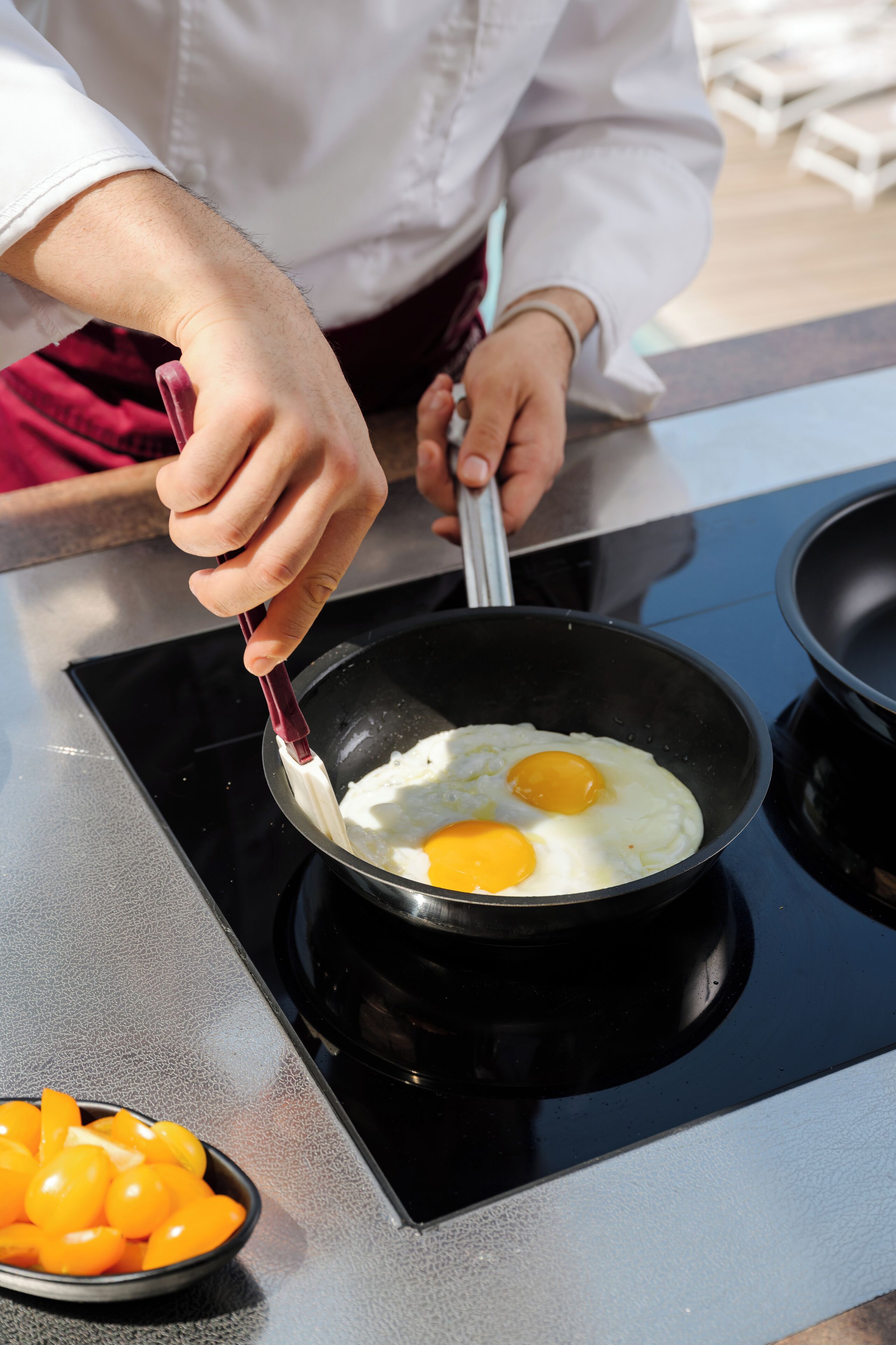 A person cooking eggs in a pan on a stovetop.