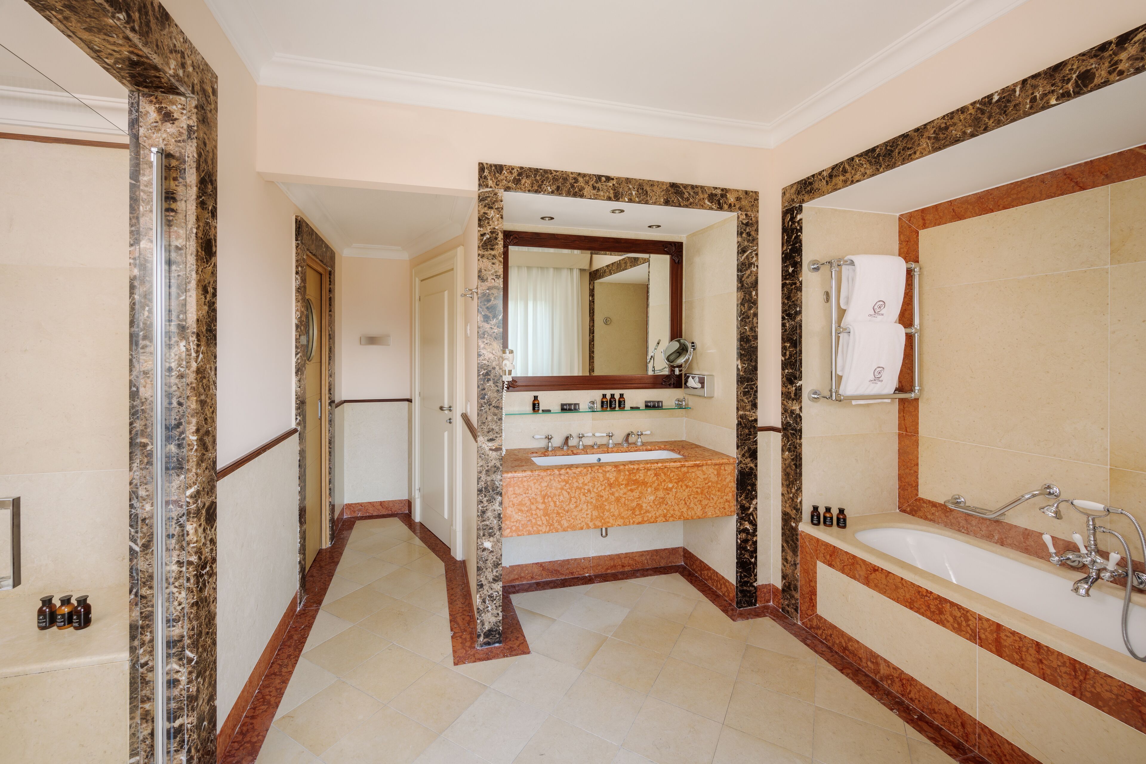 A bathroom with a marble vanity, a large mirror, a bathtub, and a shower area.