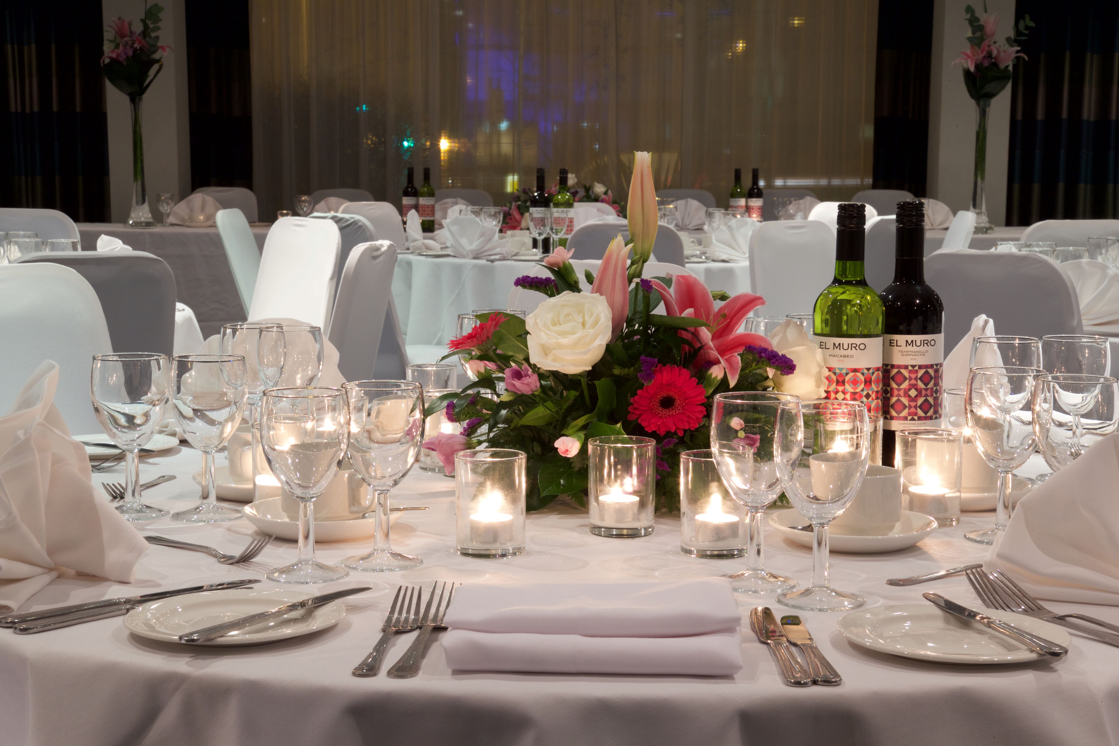 A table set for dining with candles, wine bottles, and a floral centerpiece.