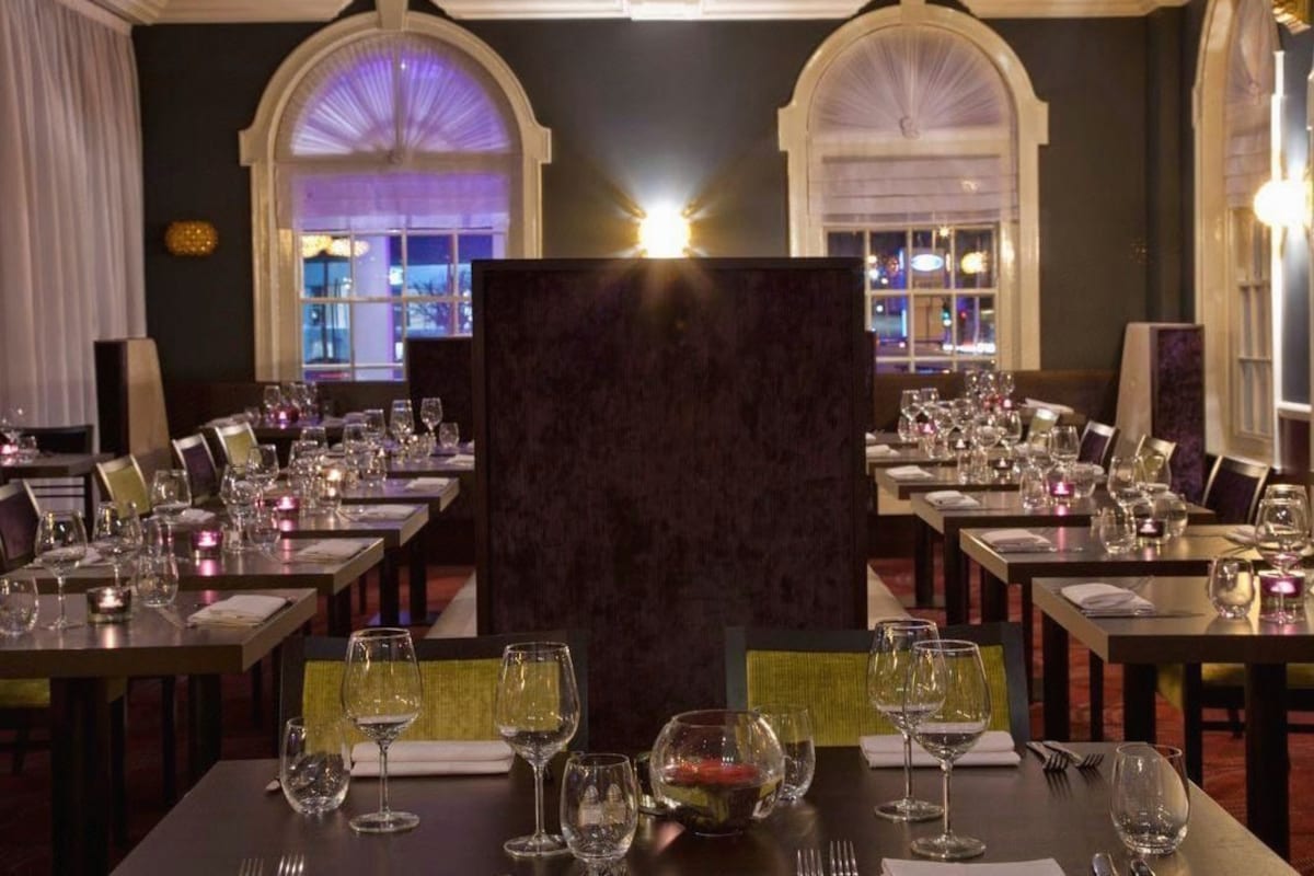 A restaurant with multiple tables set for dining, featuring a dark-toned central partition.