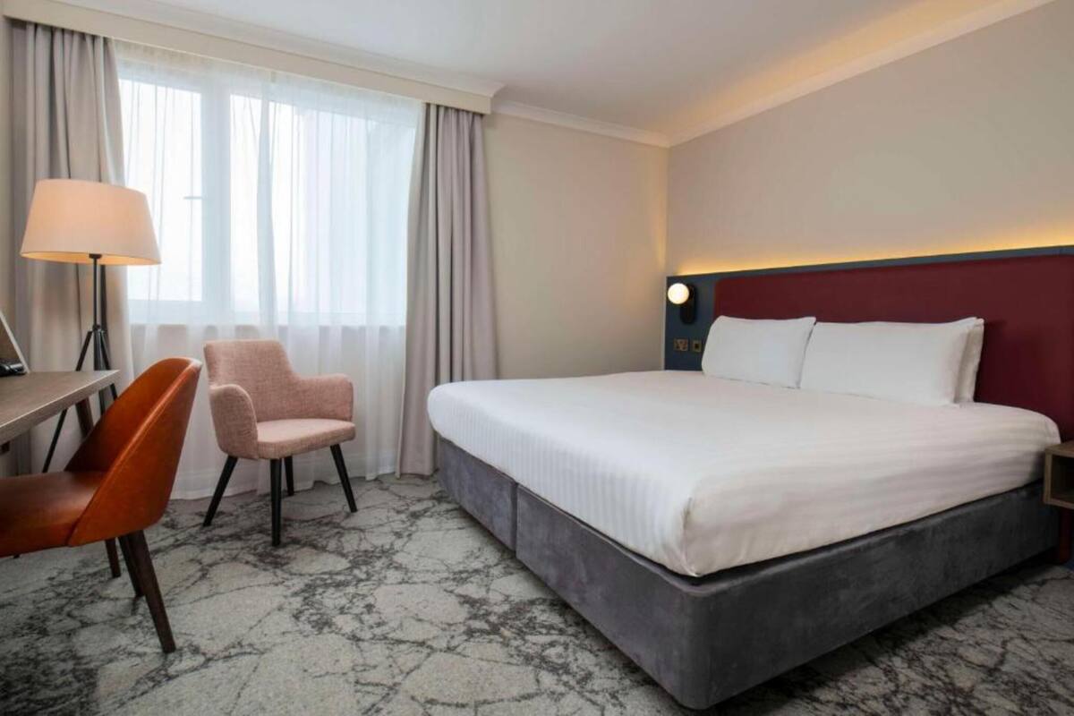 Una camera d'albergo con un letto, una scrivania, una sedia e una lampada.