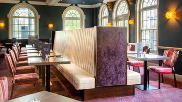 A restaurant with high-backed chairs, a long communal table, and a partition wall.